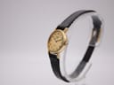 Angled side view of the Longines Presence watch on a stand, highlighting the gold-tone case and crown.