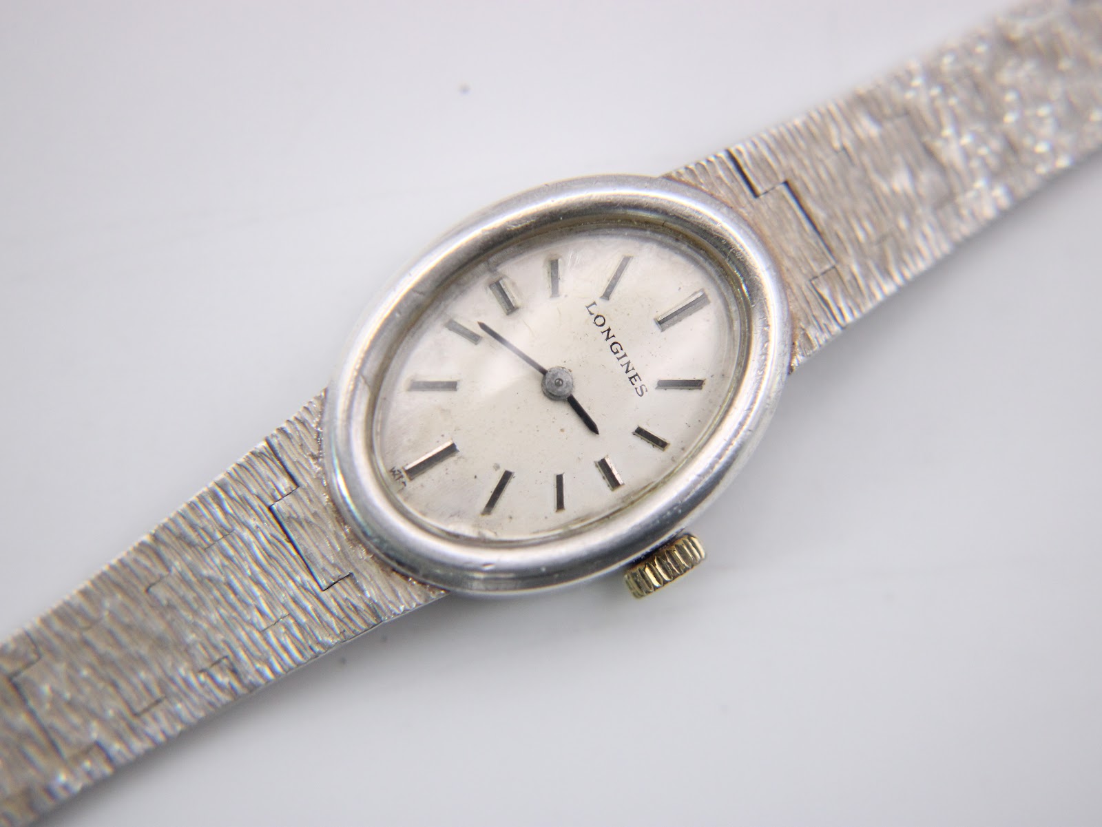 Detailed close-up of the Longines watch dial, featuring a cream face with applied baton indices and classic 'Longines' text.