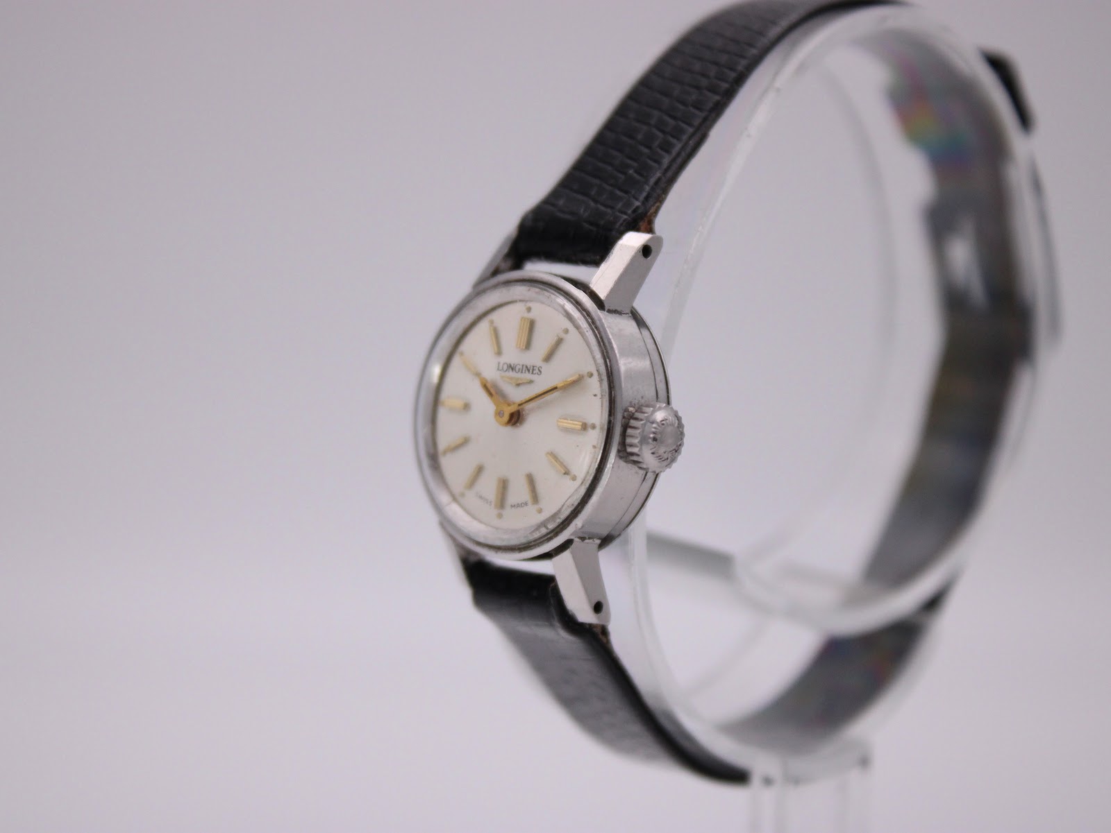 Angled side view of the Longines 7271 watch on a clear stand, showing the signed crown and silver-toned case profile.