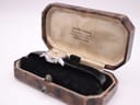 The watch is nestled in an open, vintage octagonal brown leather watch box. The cream fabric interior lining displays 'DAVID ADAMS, Watchmaker & Jeweller' address details.