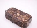 The closed vintage octagonal watch box, showcasing its distressed brown leather exterior with mottled patterns and a small, visible front clasp.