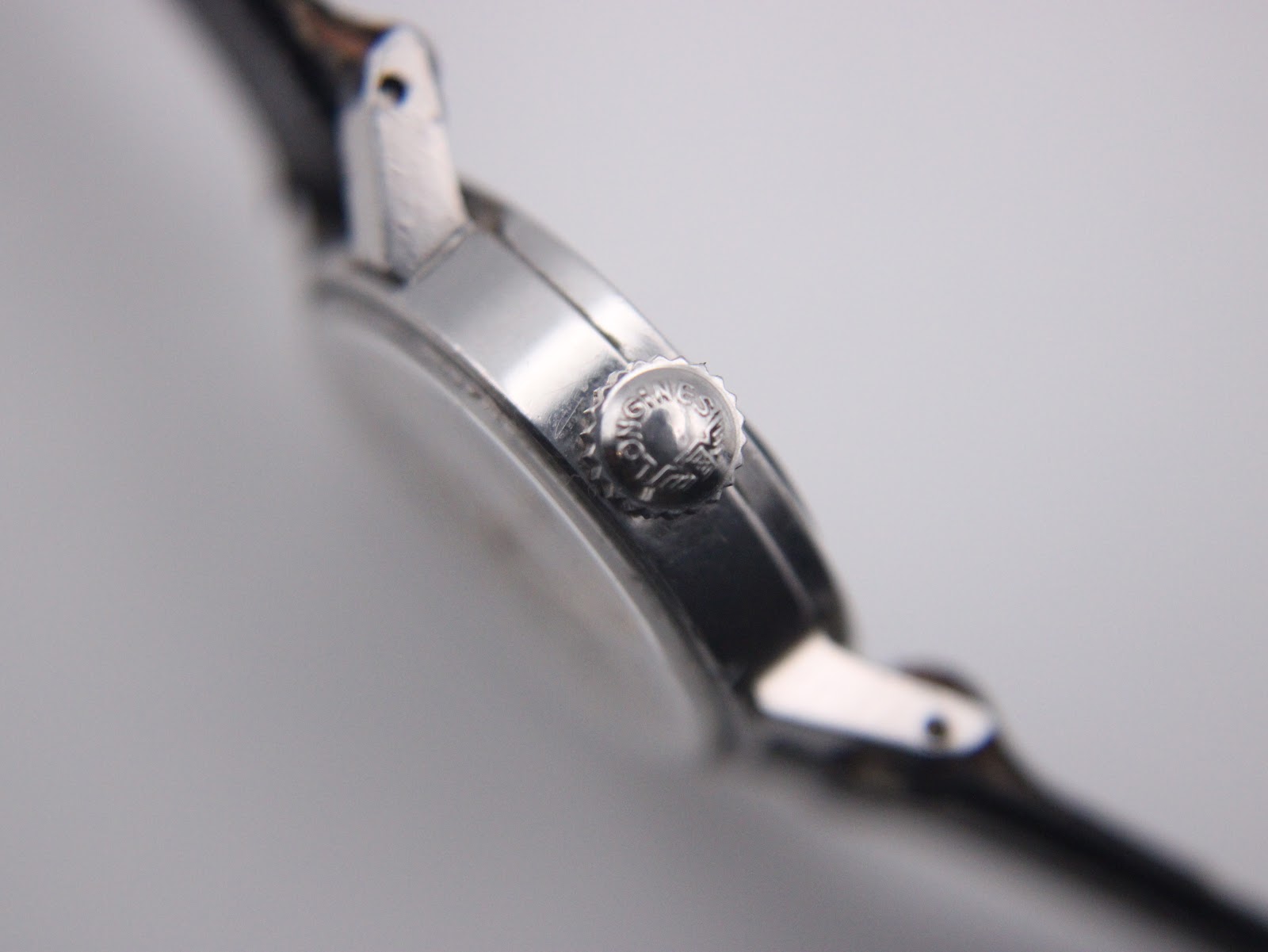 Extreme close-up of the signed Longines crown, showing the winged hourglass logo.