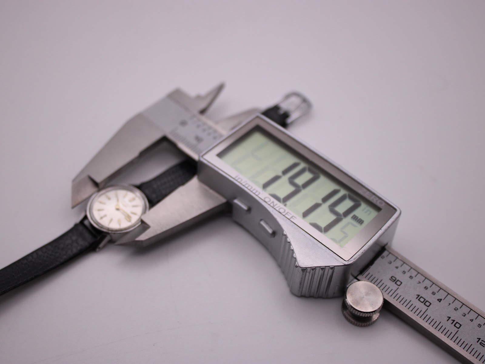 Digital caliper measuring the case diameter of the Longines watch, displaying 19.9mm.