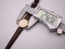 Digital caliper measuring the watch case, displaying a precise diameter of 24.28mm.