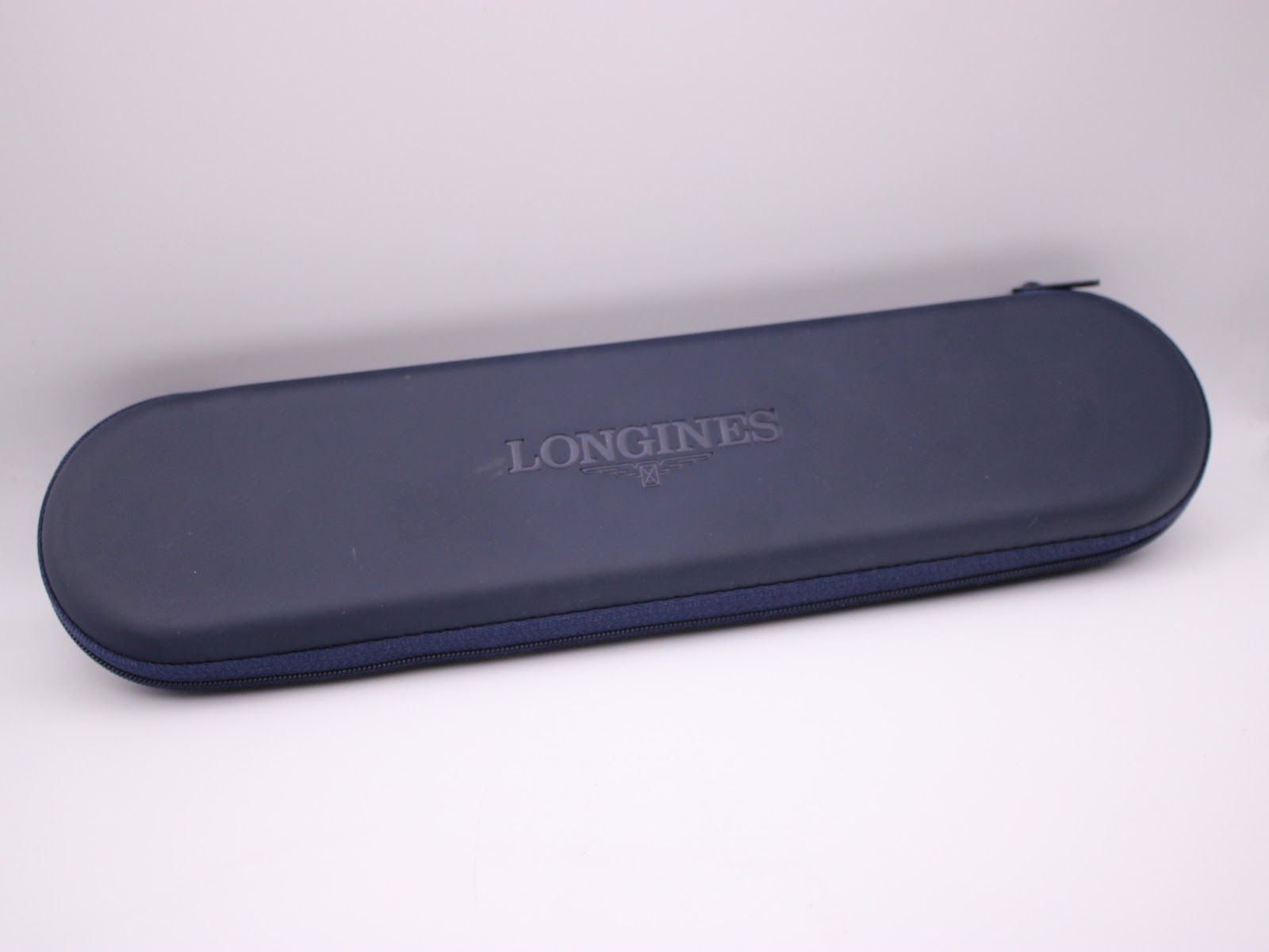 Closed blue original Longines travel case with the embossed Longines logo on its lid.