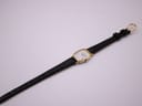 Top-down view of the Longines watch with its black leather strap fully extended on a white background.