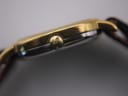 Close-up side view of the gold-plated crown of the Longines watch with an embossed logo.