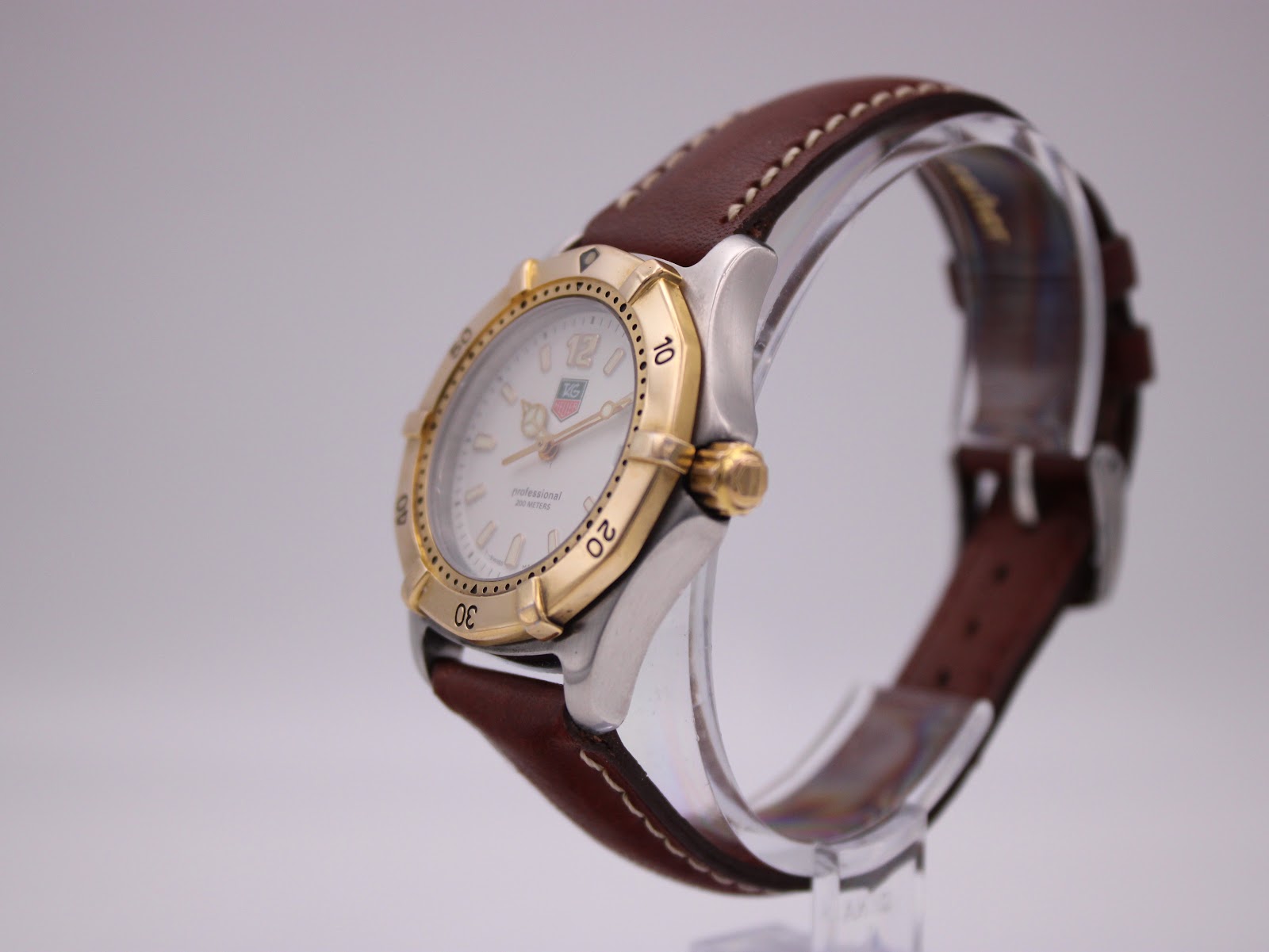 Side-angle view of the watch on a stand, highlighting the gold-plated bezel and crown on the two-tone case.