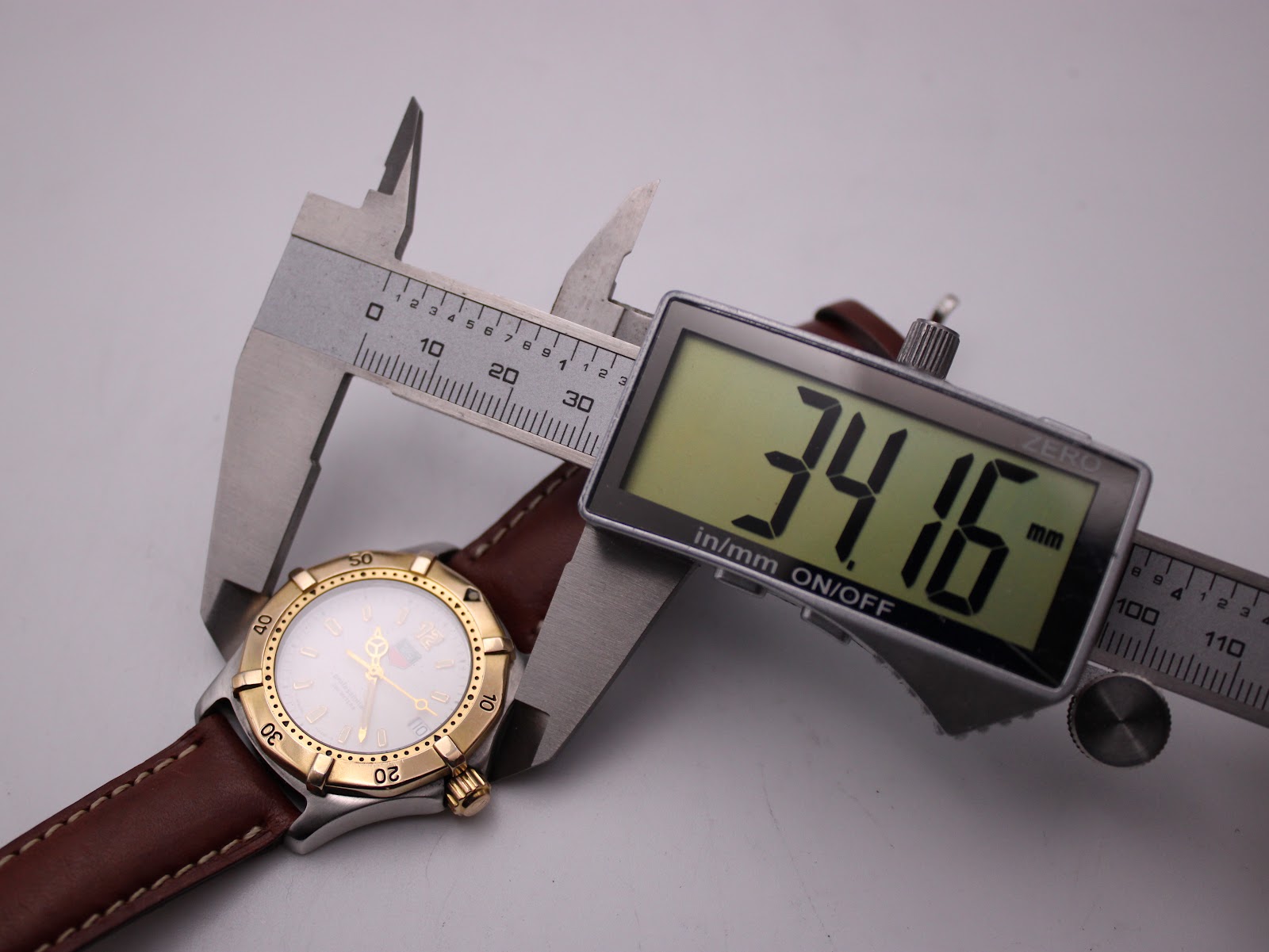View of the watch being measured by a digital caliper, displaying a case size of 34.16mm.