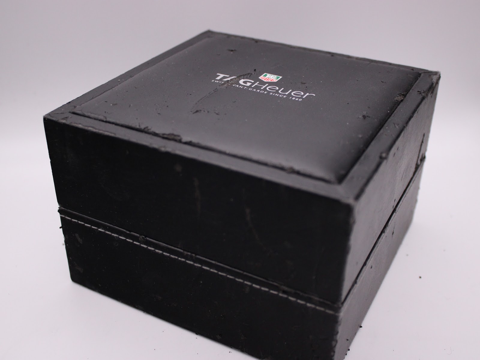 Exterior view of the original black TAG Heuer watch box, showing signs of wear.