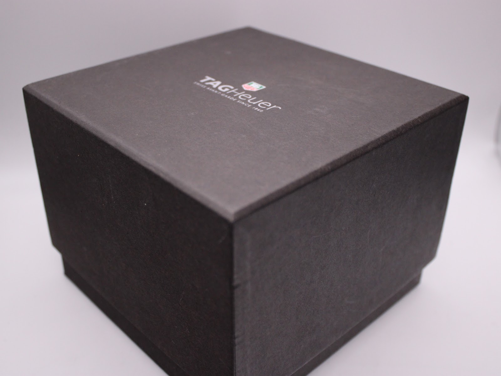 The outer dark grey cardboard box for the TAG Heuer watch, with branding.