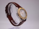 Oblique view of the watch on a stand, showcasing the profile of the stainless steel case and brown leather strap.