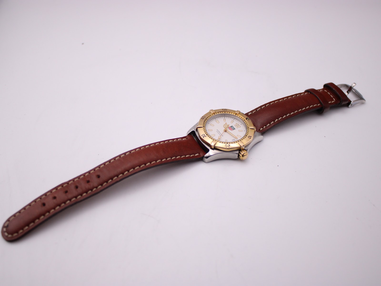 Overhead view of the TAG Heuer watch with its brown leather strap laid flat.