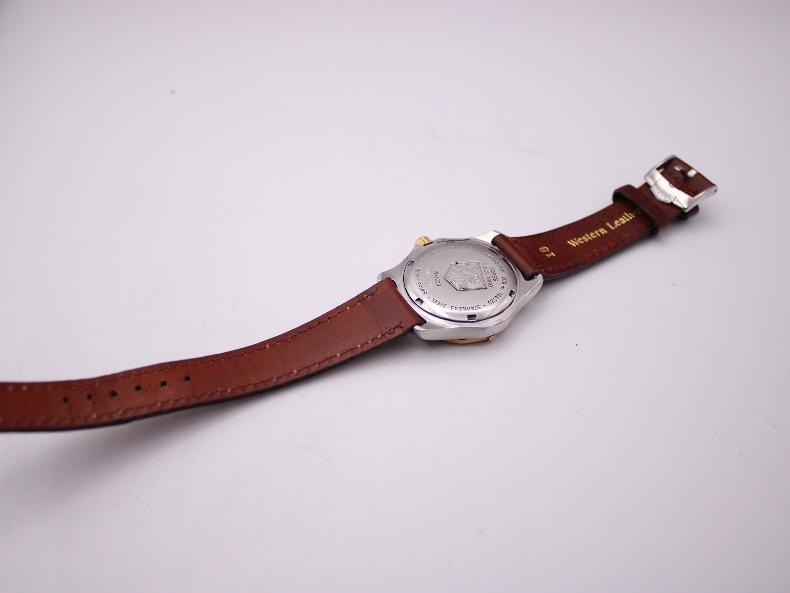 Back view of the watch laid flat, showing the case back and the full length of the brown leather strap.