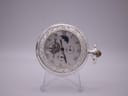 Front view of The Heritage Collection Spirit of Time pocket watch on a stand, showing its white dial, open heart, and ornate silver-plated case.