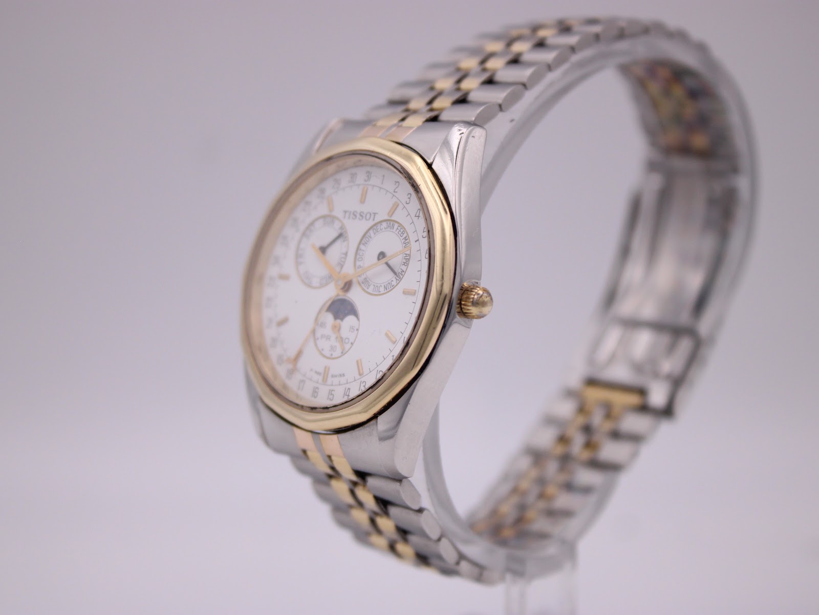 Angled side view of the Tissot PR 100 watch, highlighting the gold-plated bezel and two-tone jubilee bracelet.