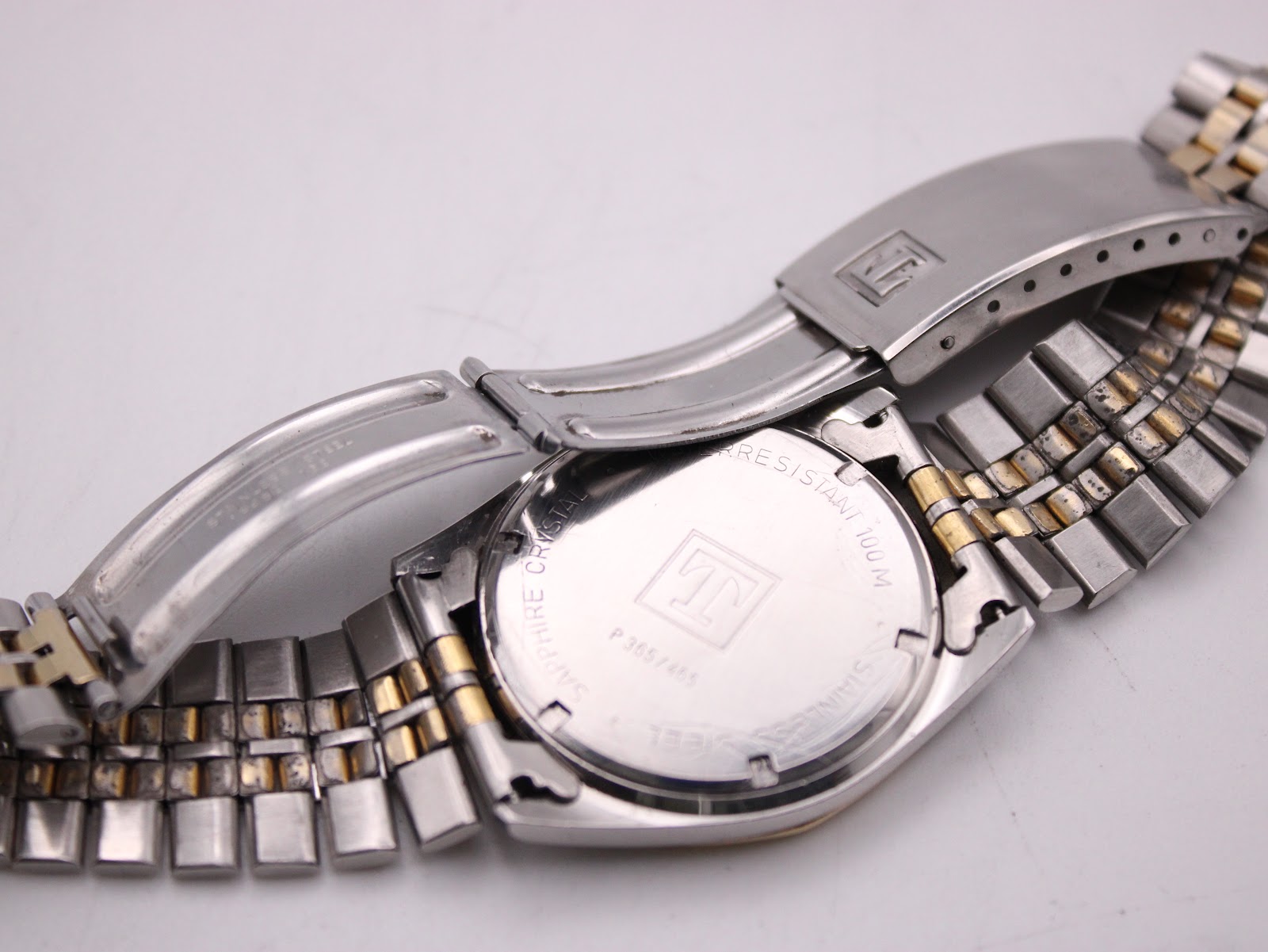 Rear view of the watch with the clasp open, showing the Tissot logo on the inner clasp and the brushed case back.