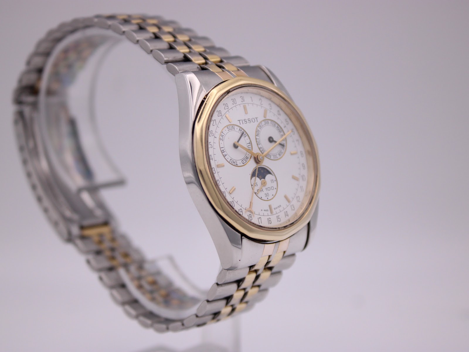 Three-quarter view of the Tissot PR 100 on a stand, showing the case profile and integrated bracelet design.