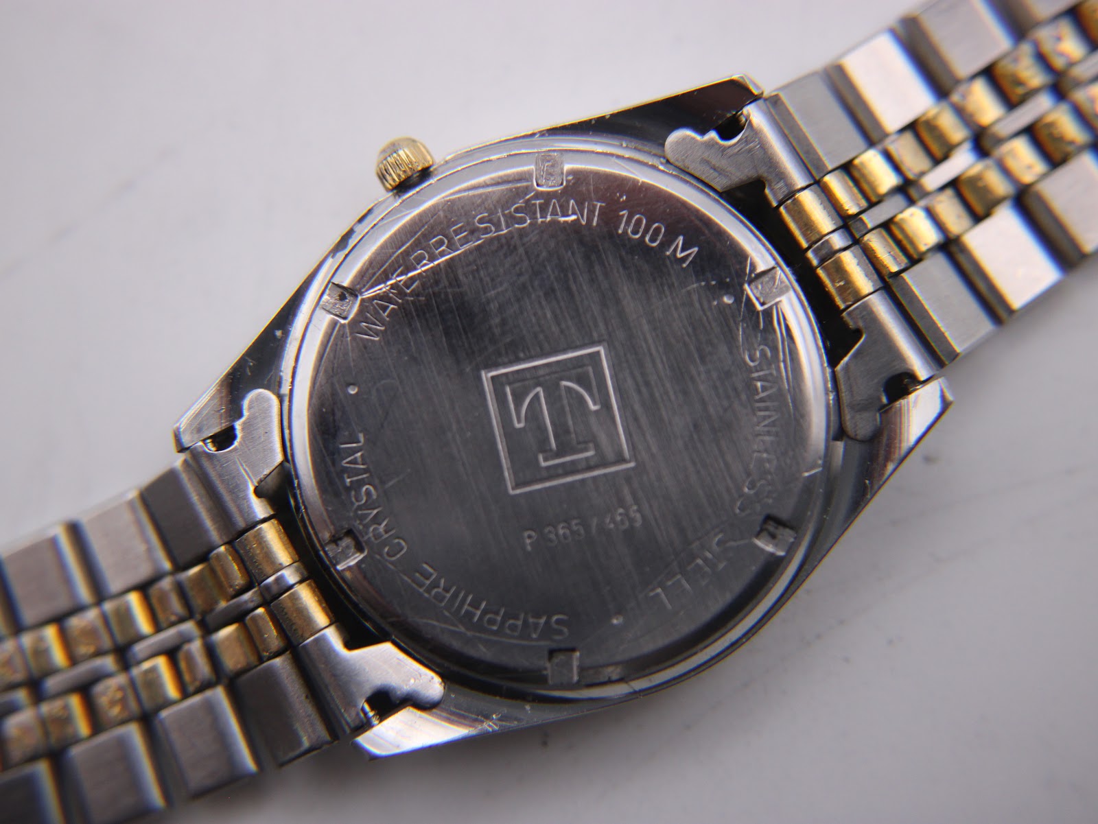 View of the Tissot PR 100 case back, showing "SAPPHIRE CRYSTAL", "WATER RESISTANT 100 M", "STAINLESS STEEL", and model number P 365/465.