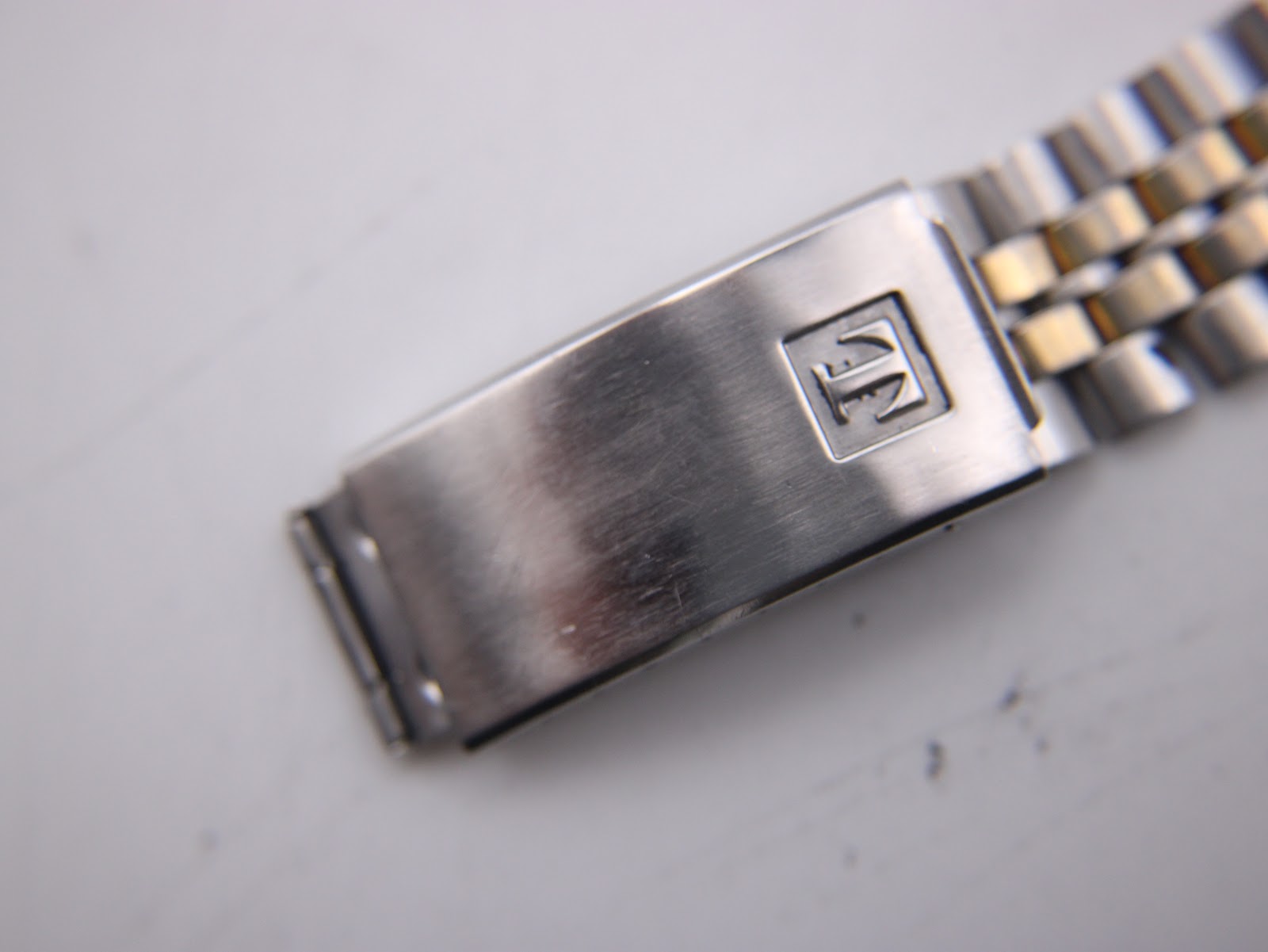 Close-up of the Tissot PR 100 two-tone bracelet clasp, featuring the signed Tissot logo.