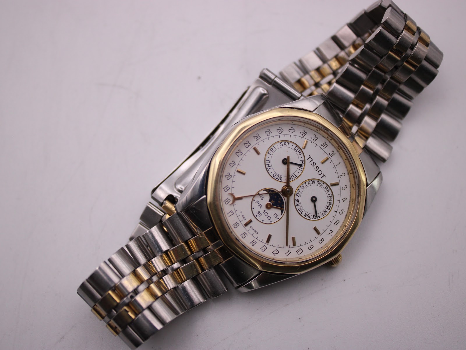 Overhead view of the Tissot PR 100 watch, displaying the complete two-tone bracelet and dial layout.