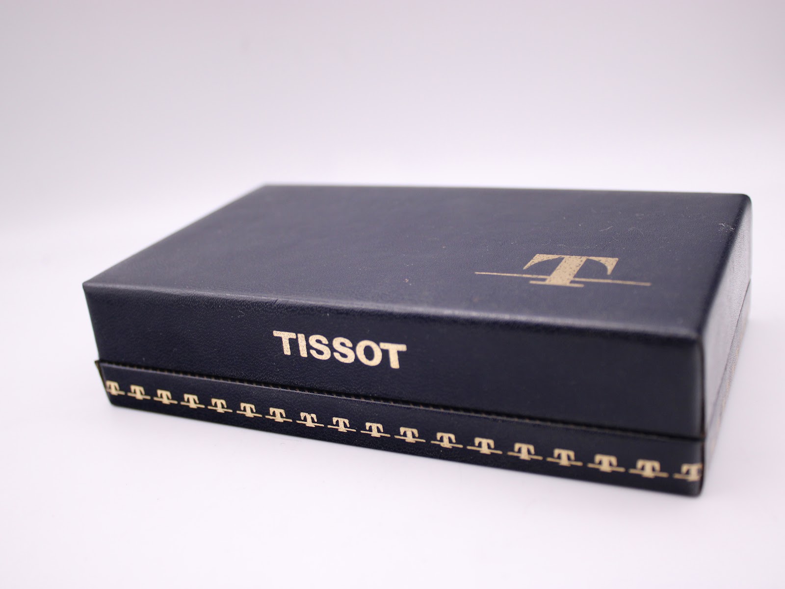 Top-down view of the closed original Tissot blue watch box with the Tissot logo embossed.