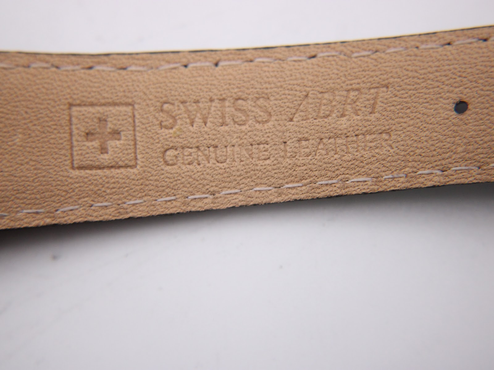 Detail shot of the genuine leather strap's underside, displaying the 'Swiss Made' cross logo and 'Genuine Leather' imprint.