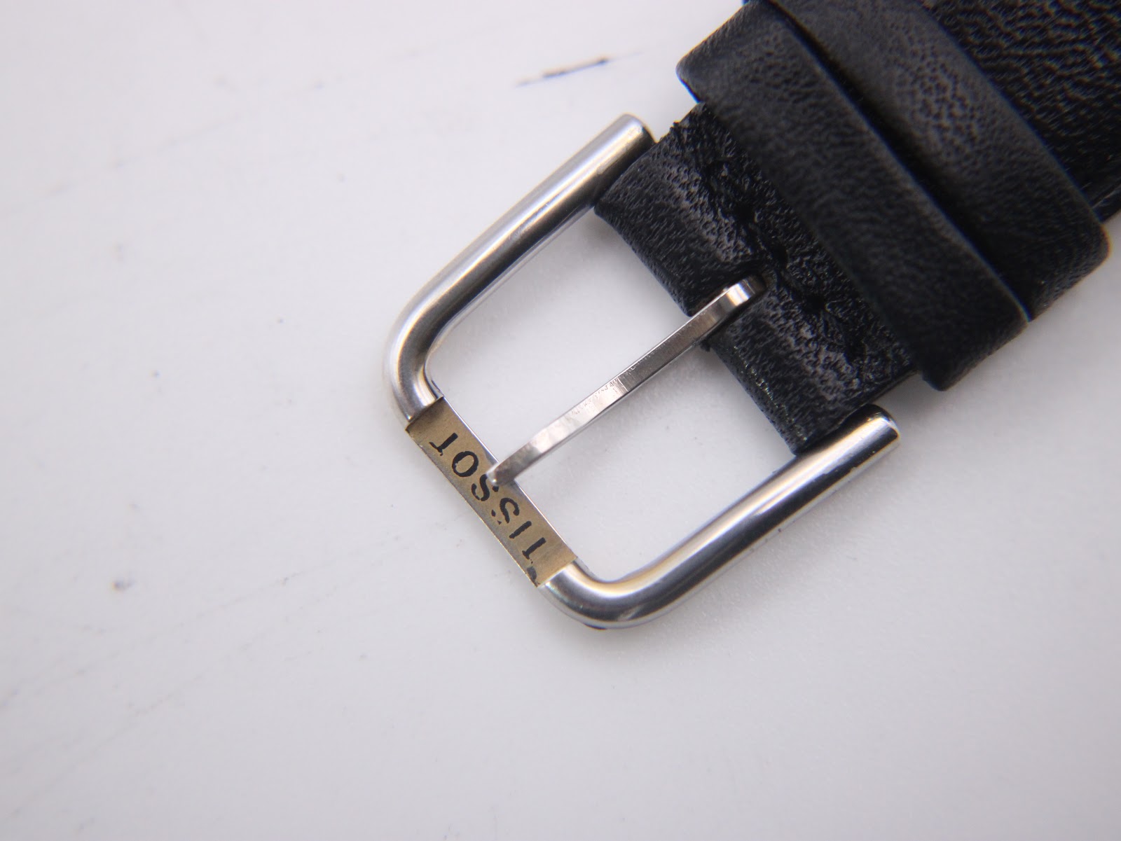 Close-up of the watch's buckle, clearly showing the 'TISSOT' brand name engraved.