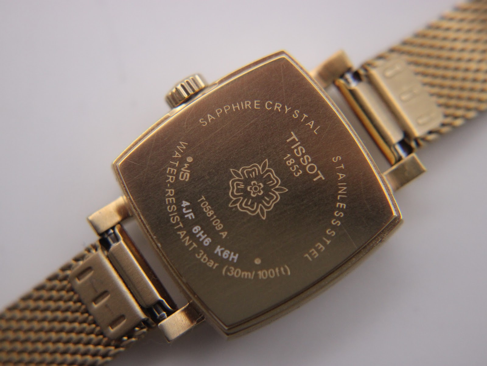 Close-up of the engraved case back, detailing 'Sapphire Crystal', 'Stainless Steel', '3bar (30m/100ft)', and the Tissot logo.