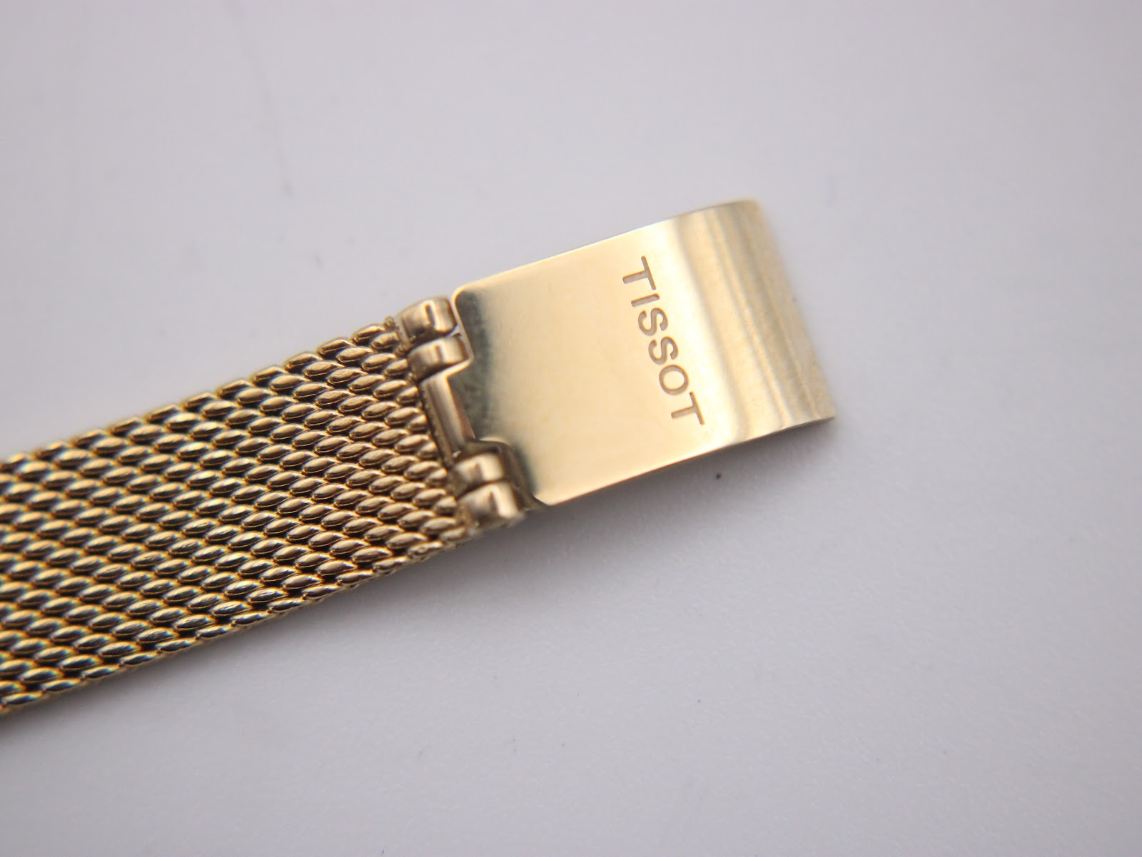 Close-up of the gold-tone fold-over clasp exterior, clearly showing the 'TISSOT' engraving.