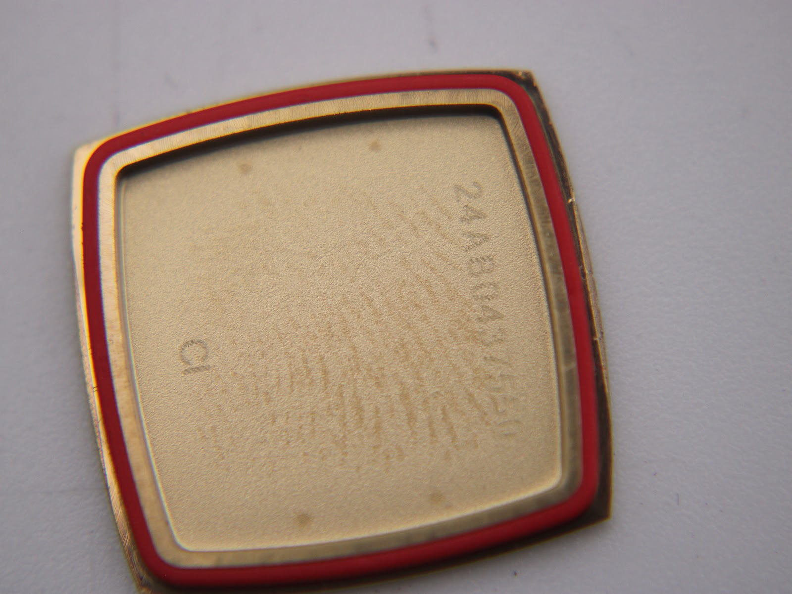 Inside view of the watch case back, showing a serial number and the red gasket.