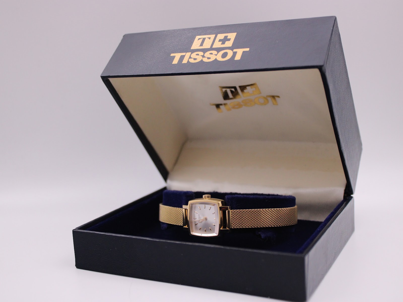 The Tissot watch displayed neatly within its original blue velour and gold branded presentation box.