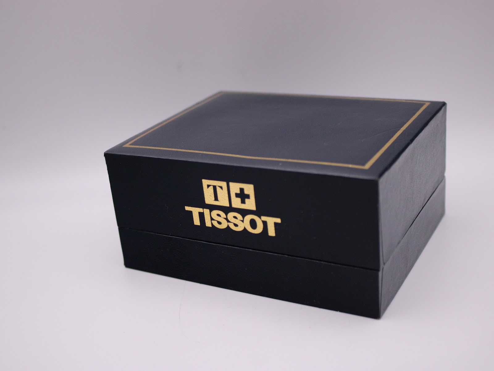 Exterior view of the closed Tissot branded black and gold presentation box.