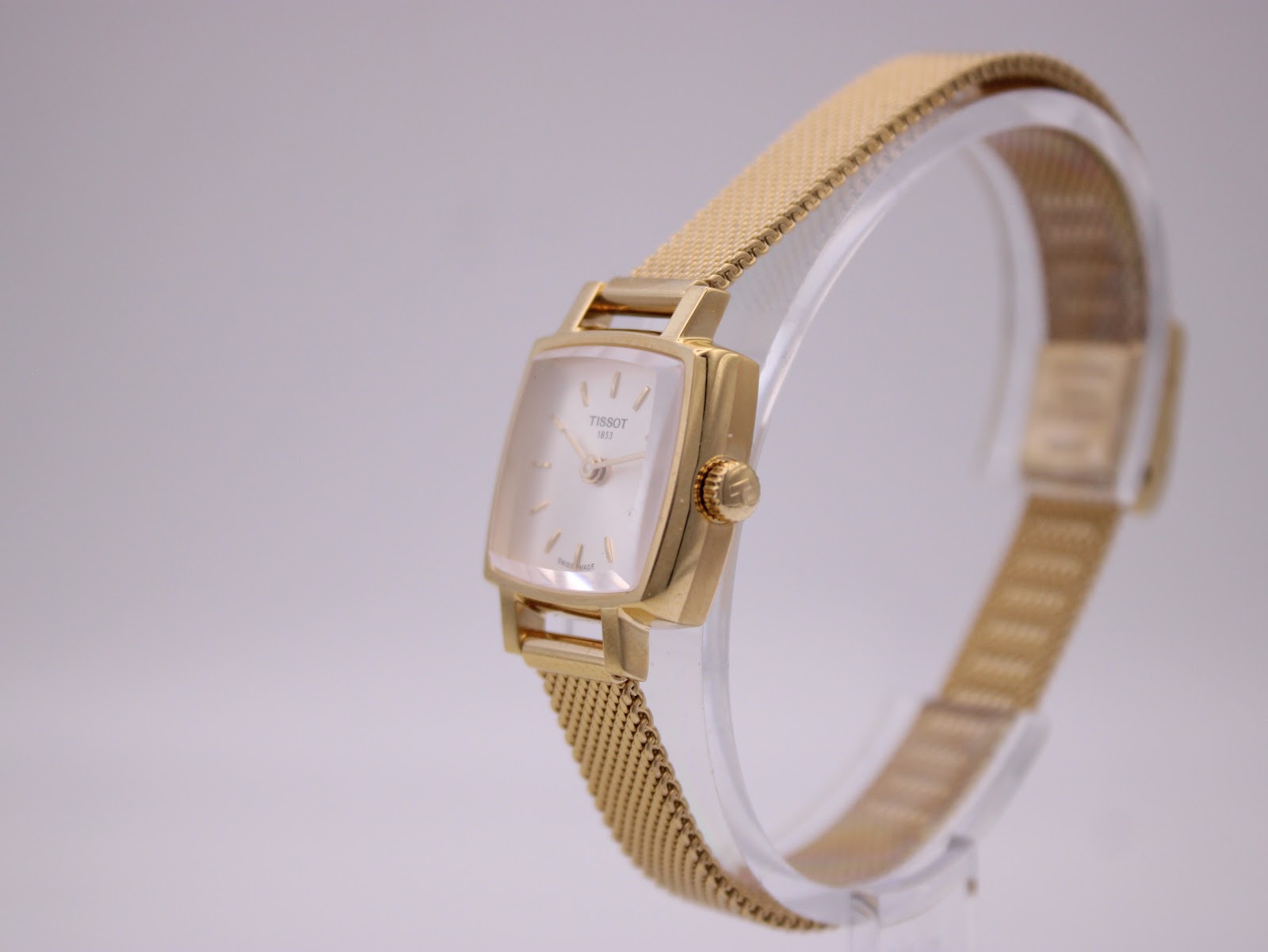 Angled side view of the Tissot T058109 A watch on a display stand, highlighting the gold-tone case and mesh bracelet.