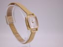 Another angled side view of the Tissot watch on its stand, showcasing the elegant lines of the case and bracelet.