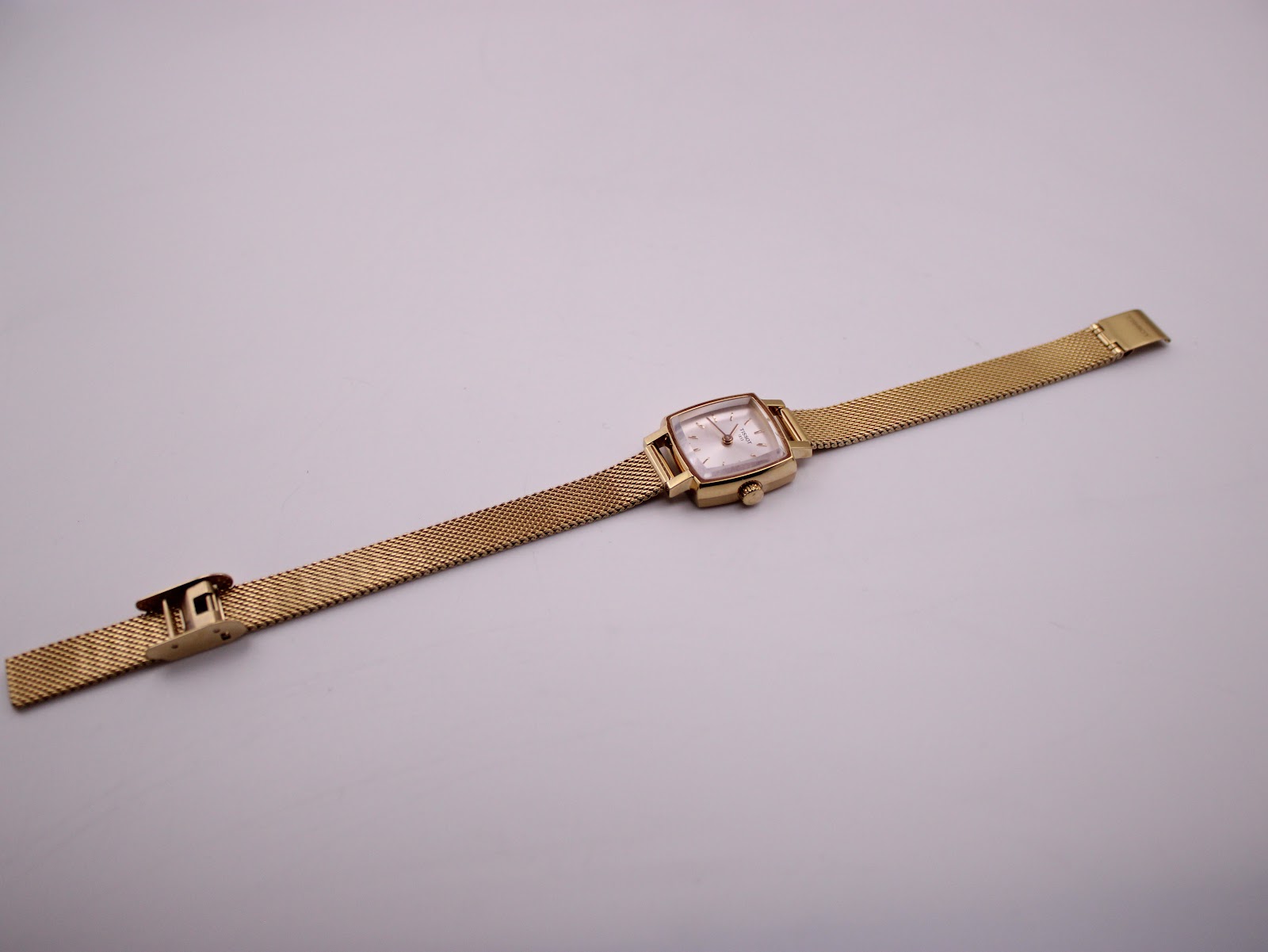 Overhead view of the entire Tissot watch with its gold-tone mesh bracelet unclasped and extended flat.