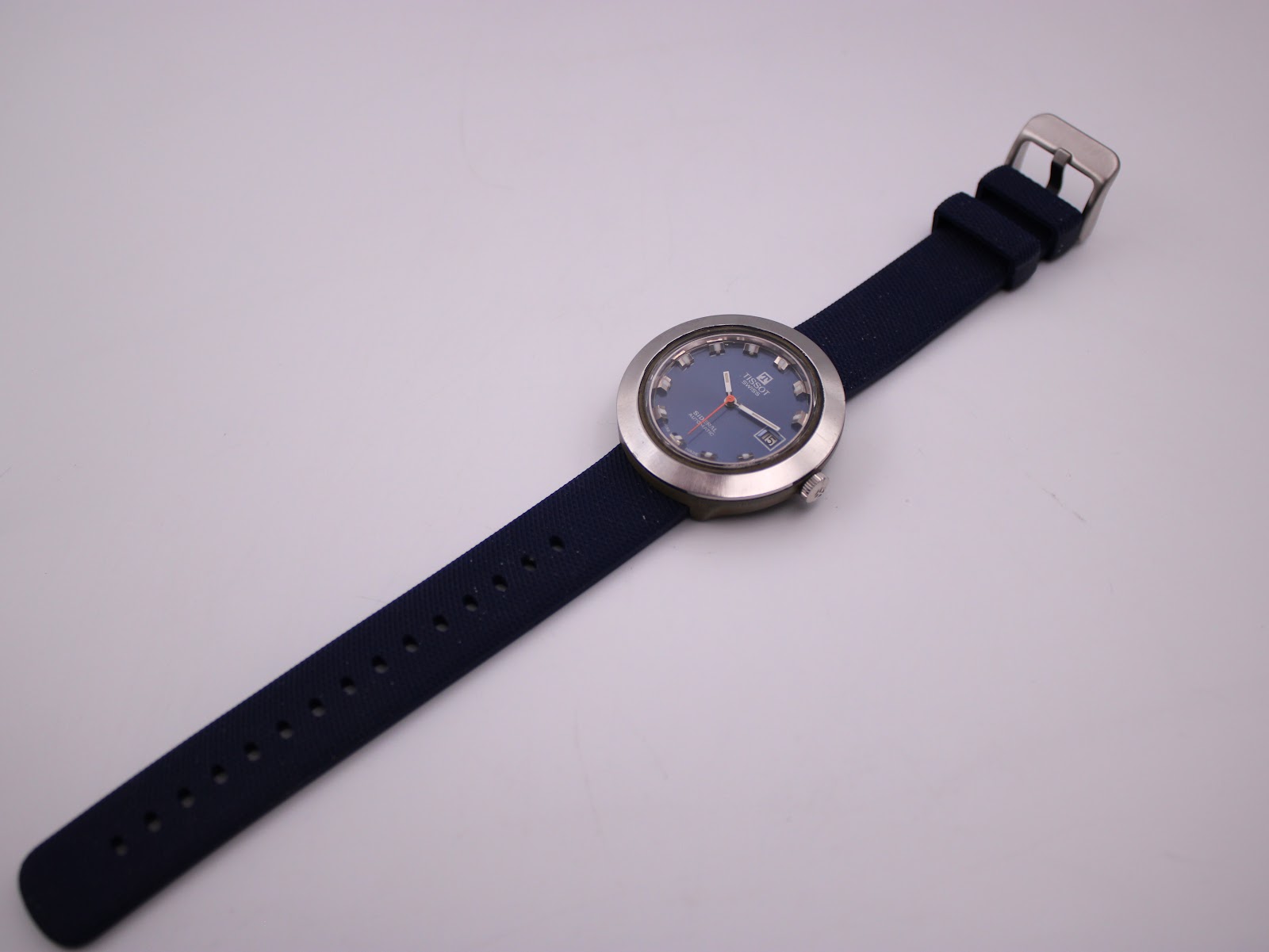 Overhead view of the entire Tissot Sideral watch laid flat, displaying the full navy rubber strap and buckle.