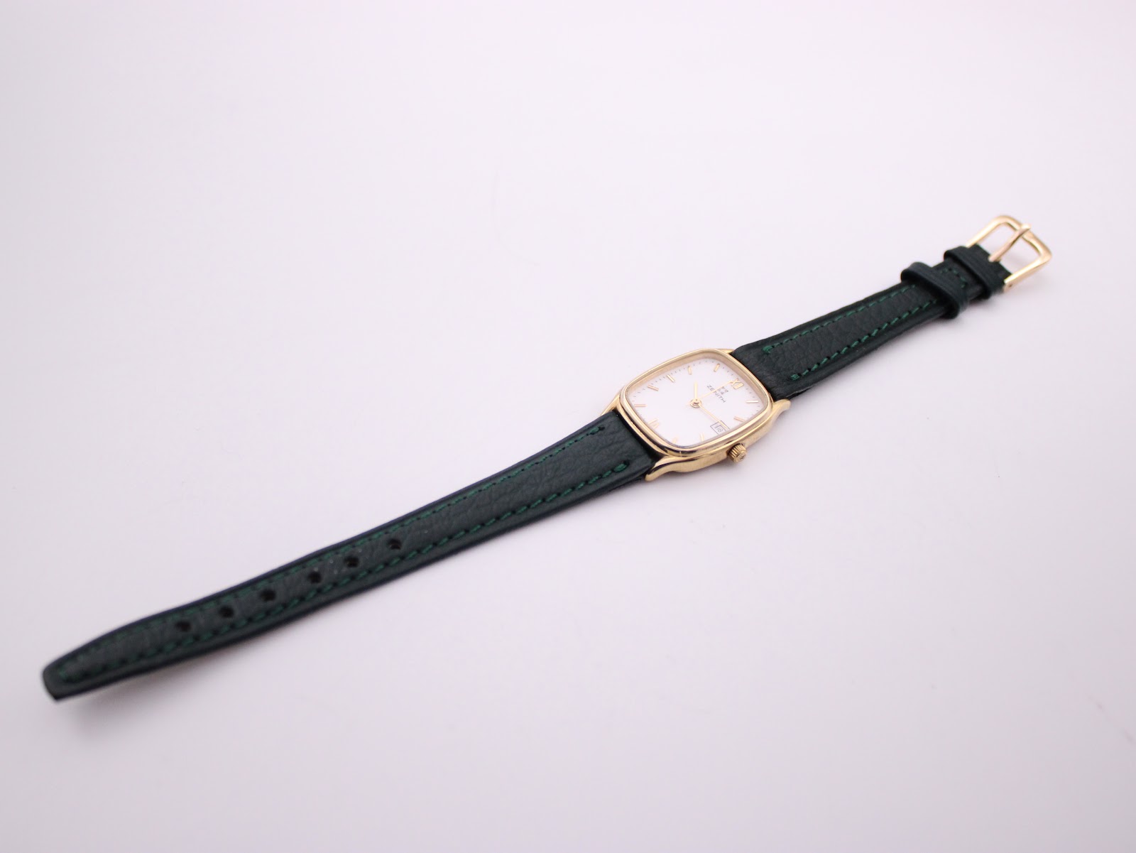 Overhead view of the Zenith watch with its green leather strap unclasped and laid flat.