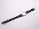 Overhead view of the Zenith watch with its green leather strap unclasped and laid flat.