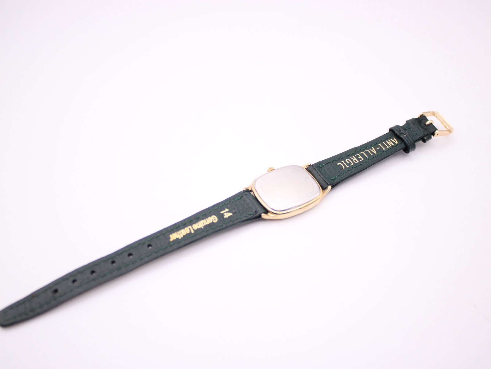 Rear view of the green leather watch strap showing "genuine leather" and "anti-allergic" text.