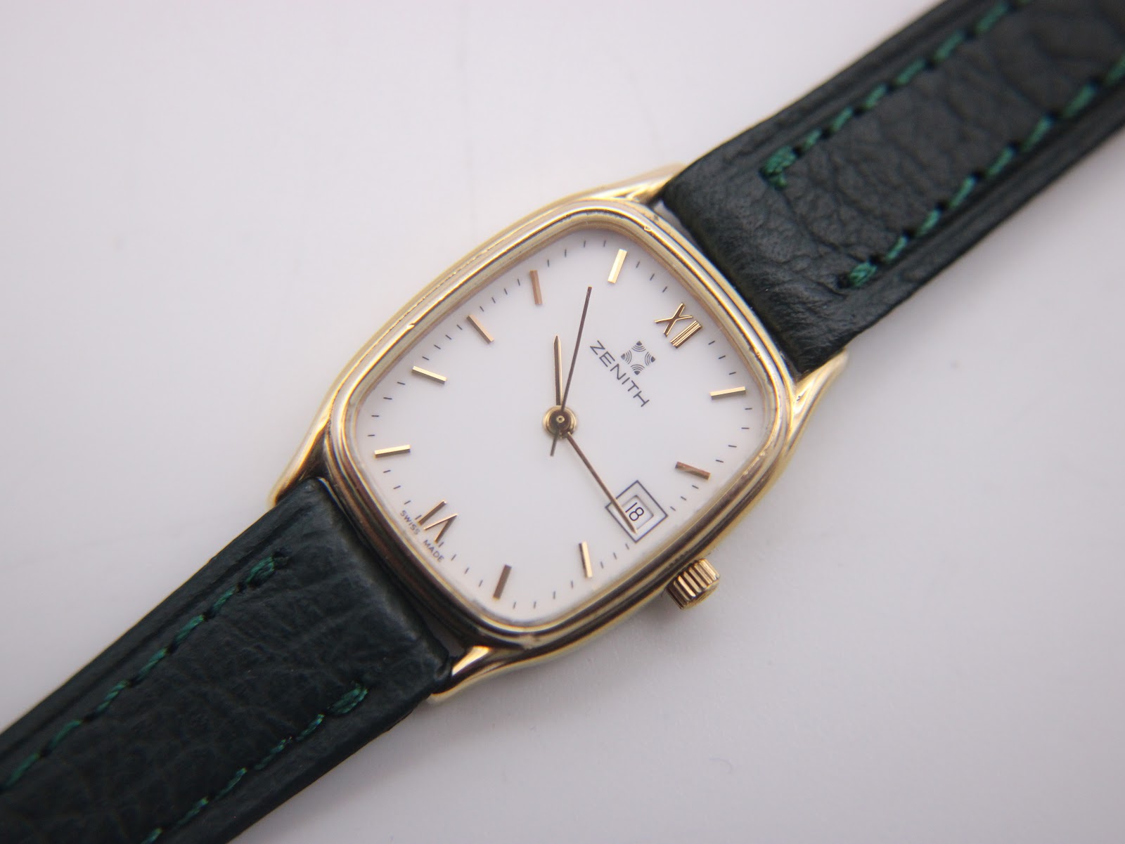 Close-up of the Zenith watch's white dial with gold Roman numerals and baton indices, date window, and "SWISS MADE" text.