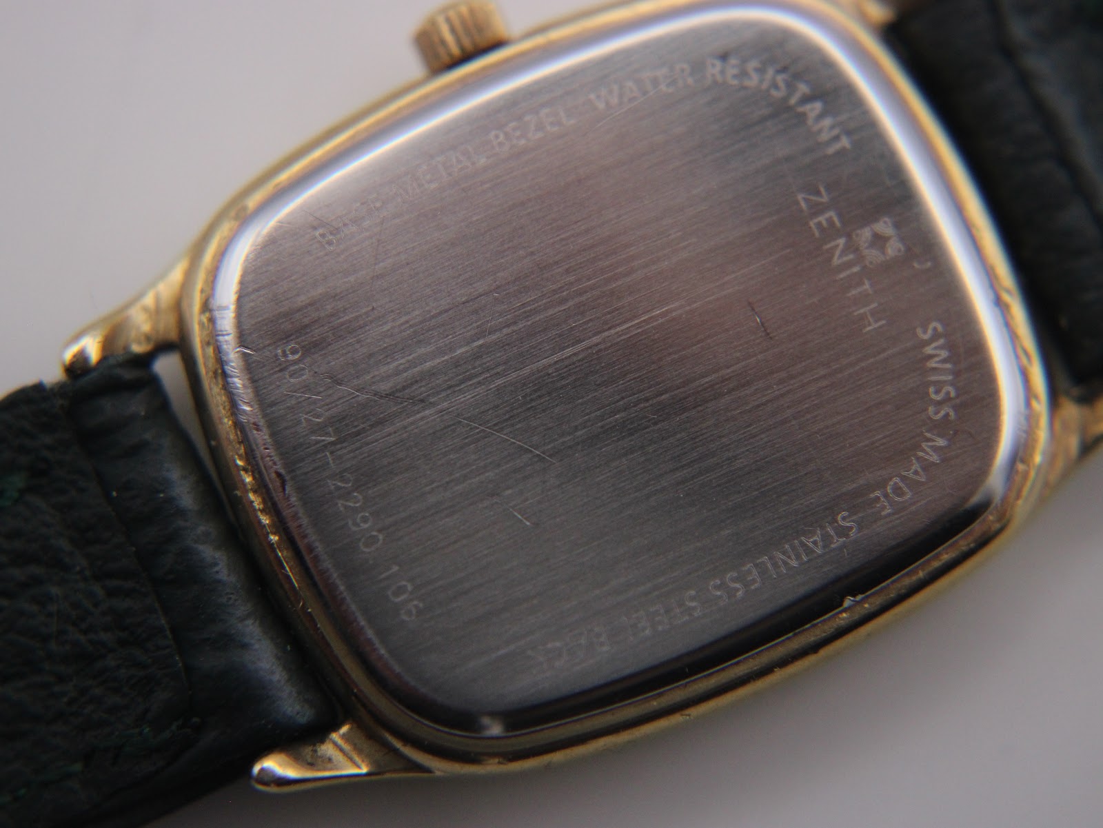 Close-up of the watch's stainless steel case back with engravings "BASE METAL BEZEL WATER RESISTANT ZENITH SWISS MADE STAINLESS STEEL BACK 90/22-2280.106".