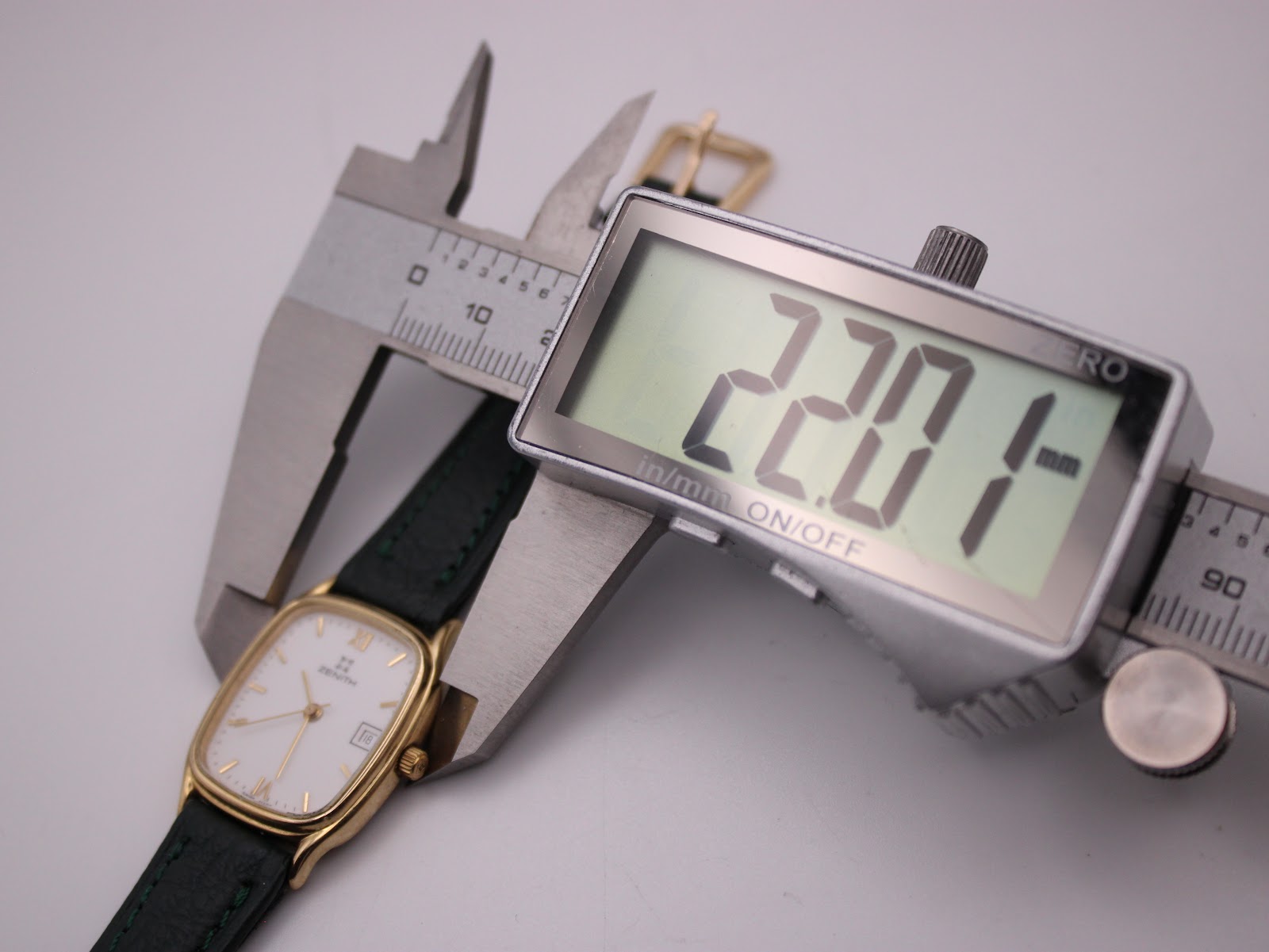 Digital caliper measuring the watch case width, displaying 22.01 mm.