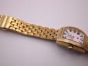 Side view of the gold-tone Michele bracelet and watch case on a white background, extended flat.