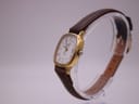 Overhead view of the Longines Presence watch laid flat, displaying the full length of the brown leather strap with gold buckle.