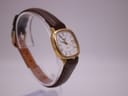 Back view of the Longines Presence watch laid flat, showing the case back and the underside of the brown leather strap with 'Anti-Allergy Leather' text.