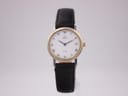 Front view of the Omega De Ville two-tone quartz watch with white Roman numeral dial, on a clear display stand.