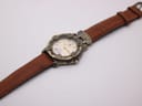 Overhead view of the Camel Trophy watch with its brown leather strap laid flat and extended on a white surface.