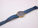 Overhead view of the Citizen watch with its blue dial and gold-tone case, laid flat with the blue leather strap extended.