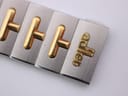Close-up of the integrated two-tone bracelet with "adler" signed on a gold-plated link.